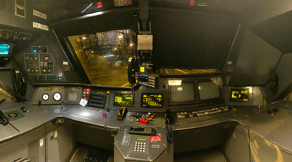 View inside a train’s driver cabin with two seats screens controls and buttons for driving the train
